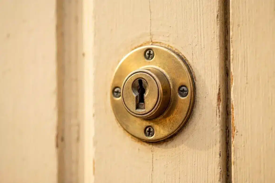 Primer plano de una cerradura convencional en puerta residencial de madera, antes de instalar un bombín de alta seguridad